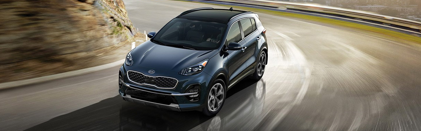 Blue Kia Sportage driving around a bend