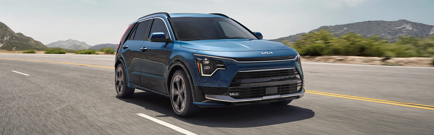 Front view of 2025 Kia Niro driving down a desert mountain highway