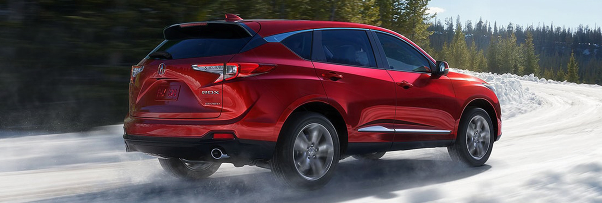 Rear angled view of a red Acura RDX in motion