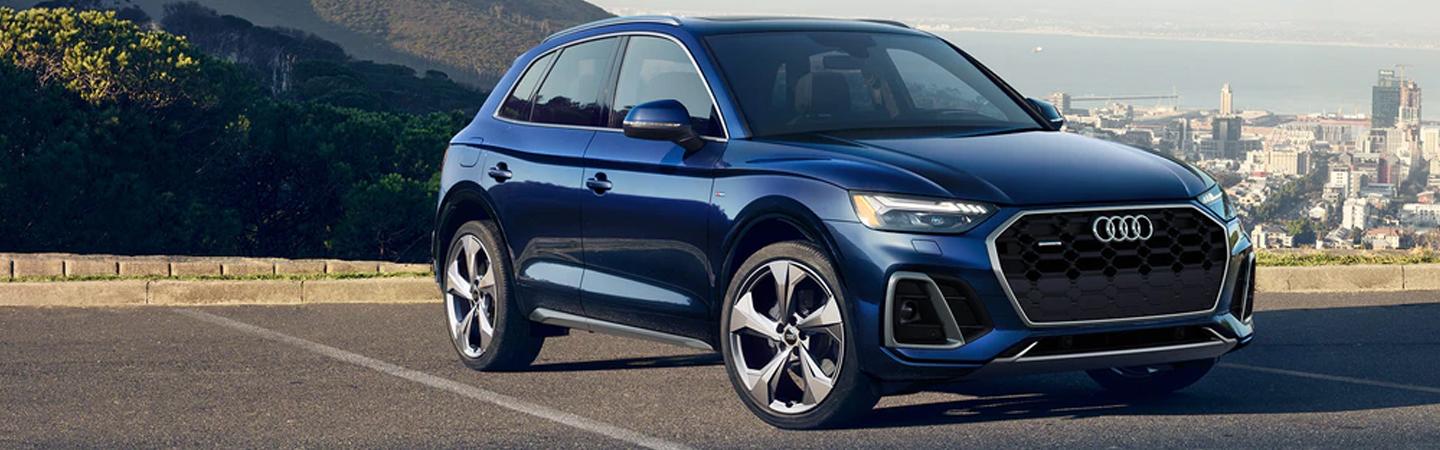A blue Audi SUV parked overlooking a city