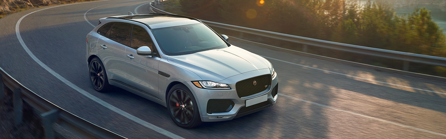 Silver Jaguar F-PACE rounding a mountain bend