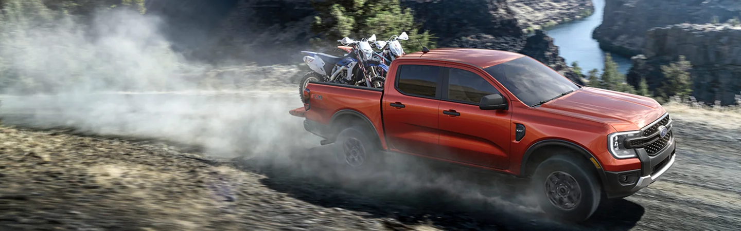 red 2025 Ford Ranger Raptor with 2 motorcycles in back in motion offroad