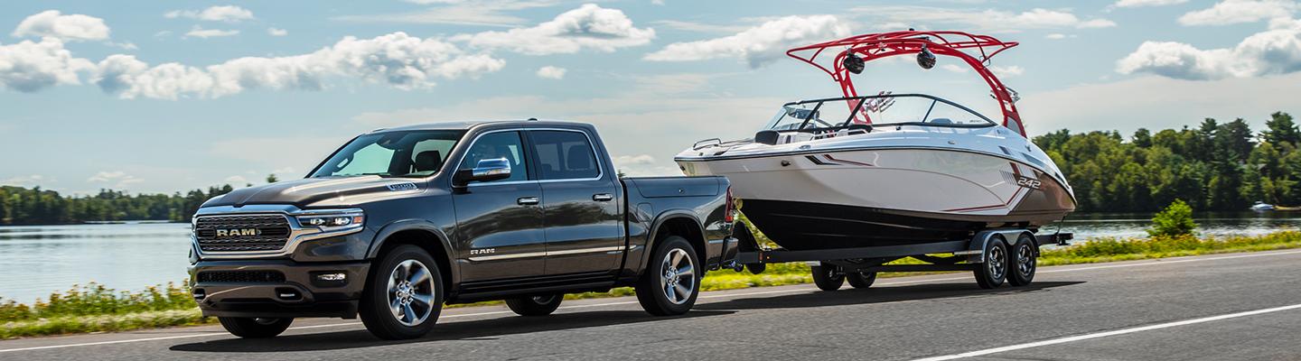 Grey RAM 1500 towing a boat down the road.