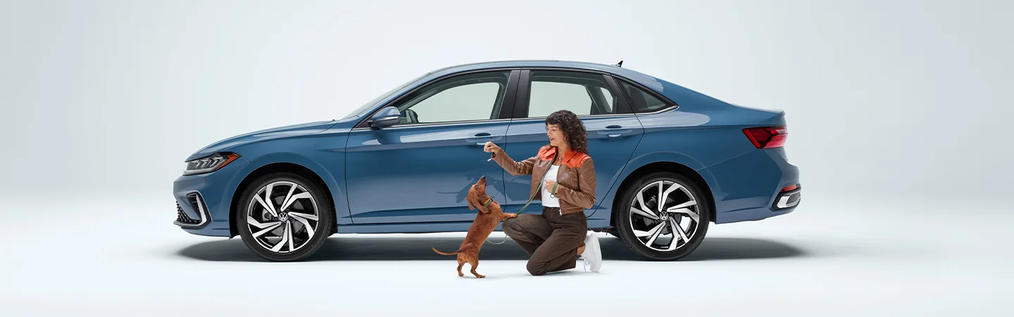 blue 2025 Volkswagen Jetta SEL with person and dog playing out side the car