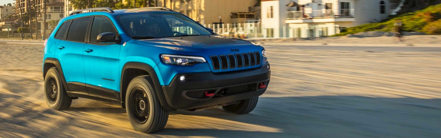 Blue Jeep Cherokee in motion through the sand
