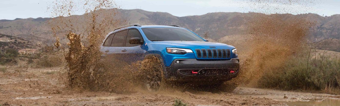 Blue Jeep Cherokee riding through a mud trail
