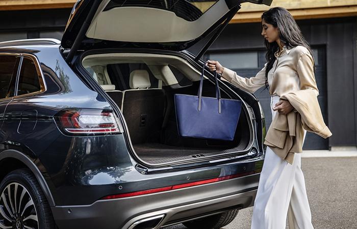 A woman loading a purse into a 2022 Lincoln Nautilus trunk