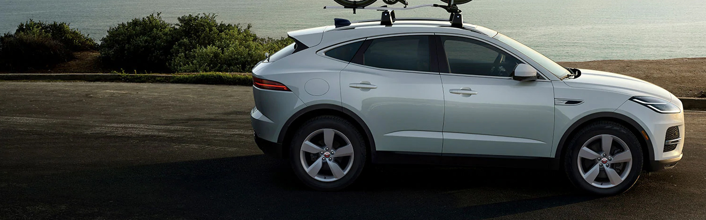 White 2021 Jaguar E-PACE driving next to the beach