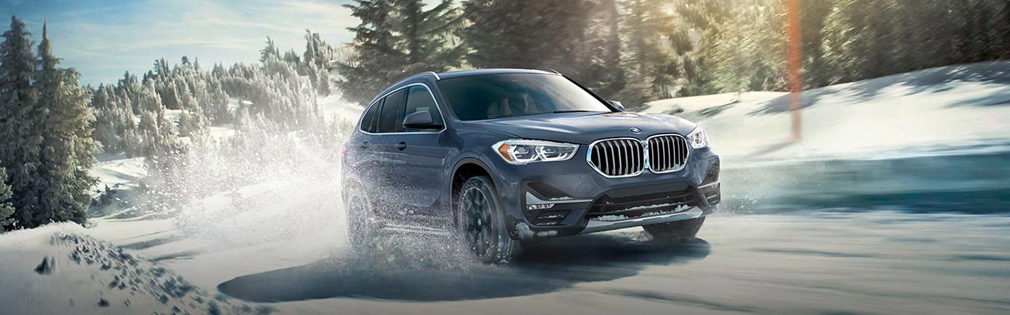 Blue 2021 BMW X1 Driving Through Snow on Trail