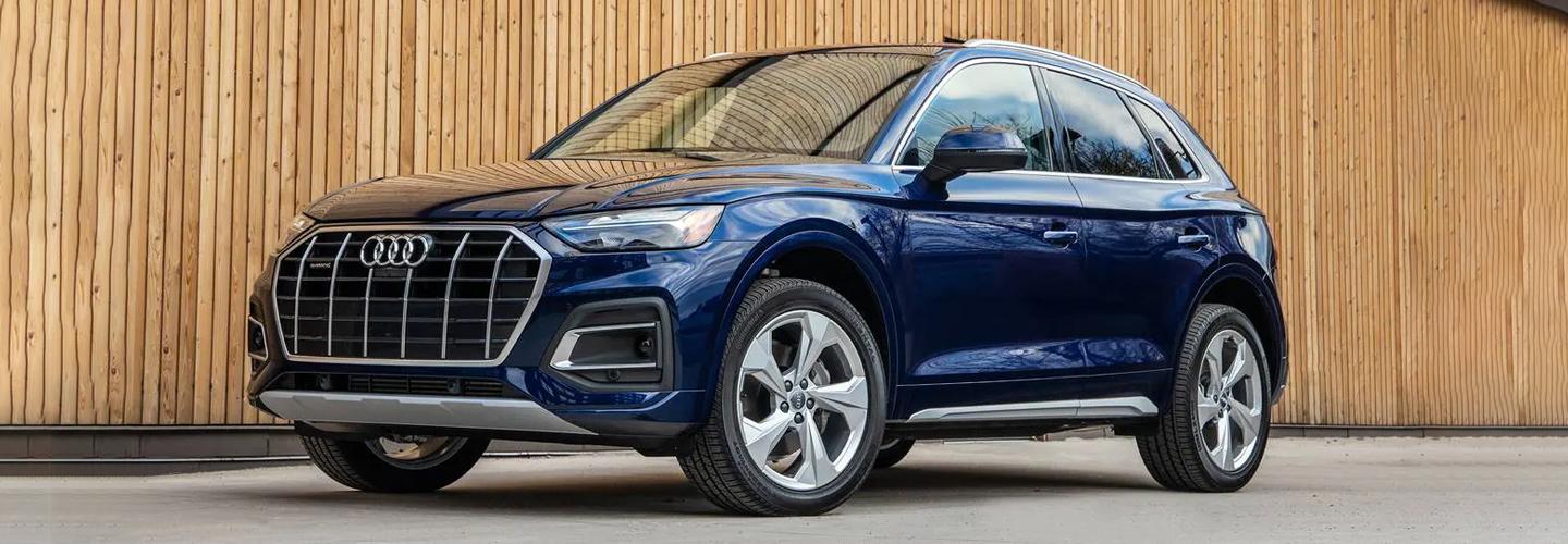 Blue Audi parked by wooden fence