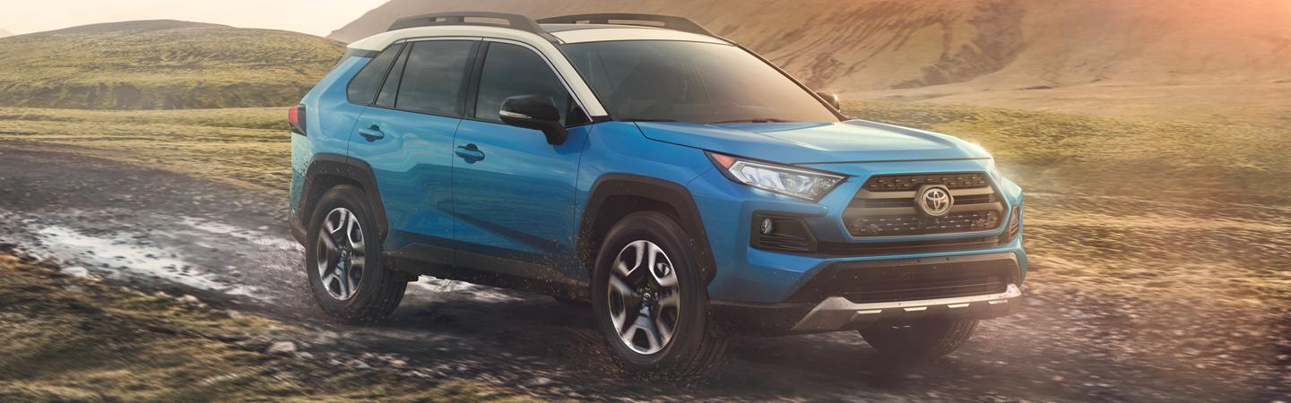 Blue 2020 Toyota RAV4 driving on gravel road