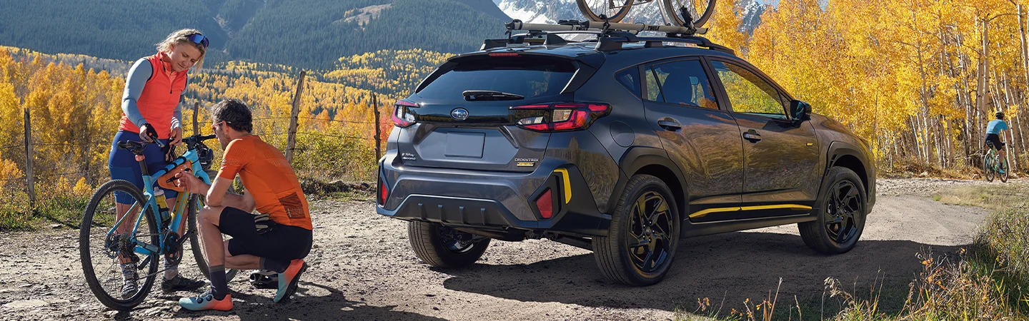 People adjusting a mountain bike in front of a parked 2025 Subaru Crosstrek Leesburg FL
