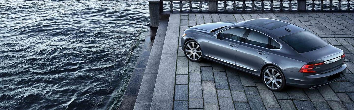 Driver’s side view of S90 parked next to water