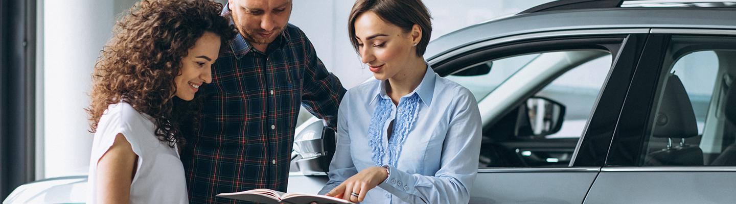 A dealership employee reviewing documents with customers