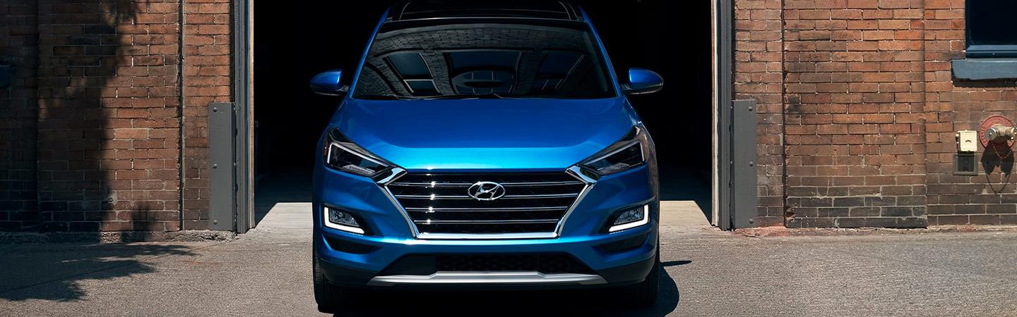 Front view of blue Tucson pulling out of garage