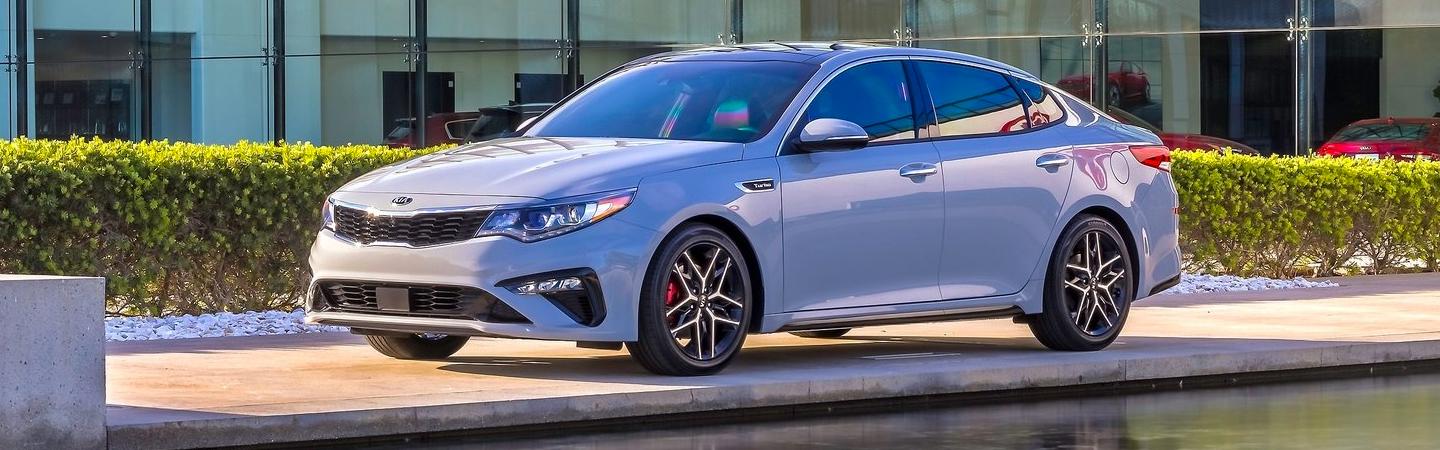 White Optima parked by a bush