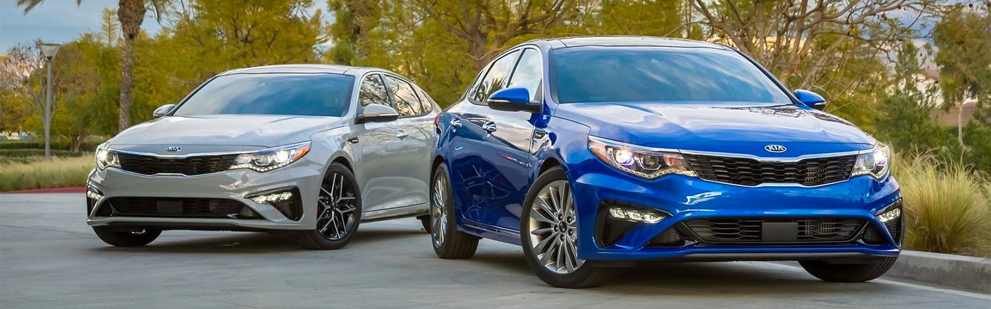 Blue and silver Optimas parked side by side