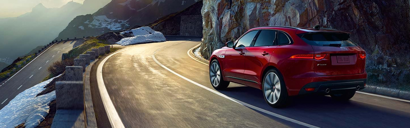 Red Jaguar F-PACE driving through the mountains