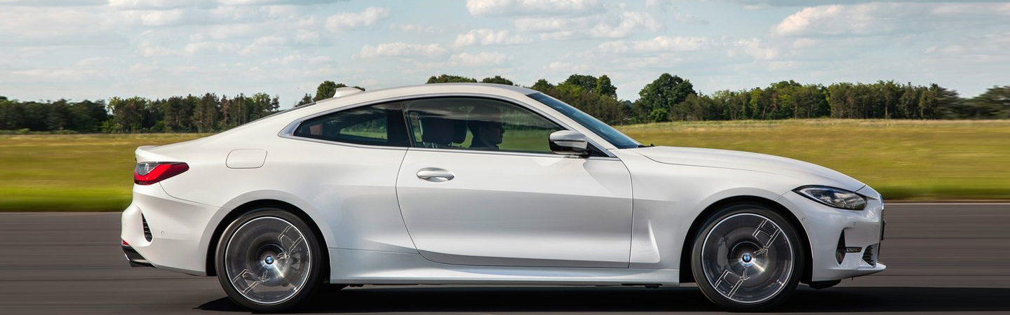 Side view of white 2021 BMW 4 Series Coupe Driving On Road