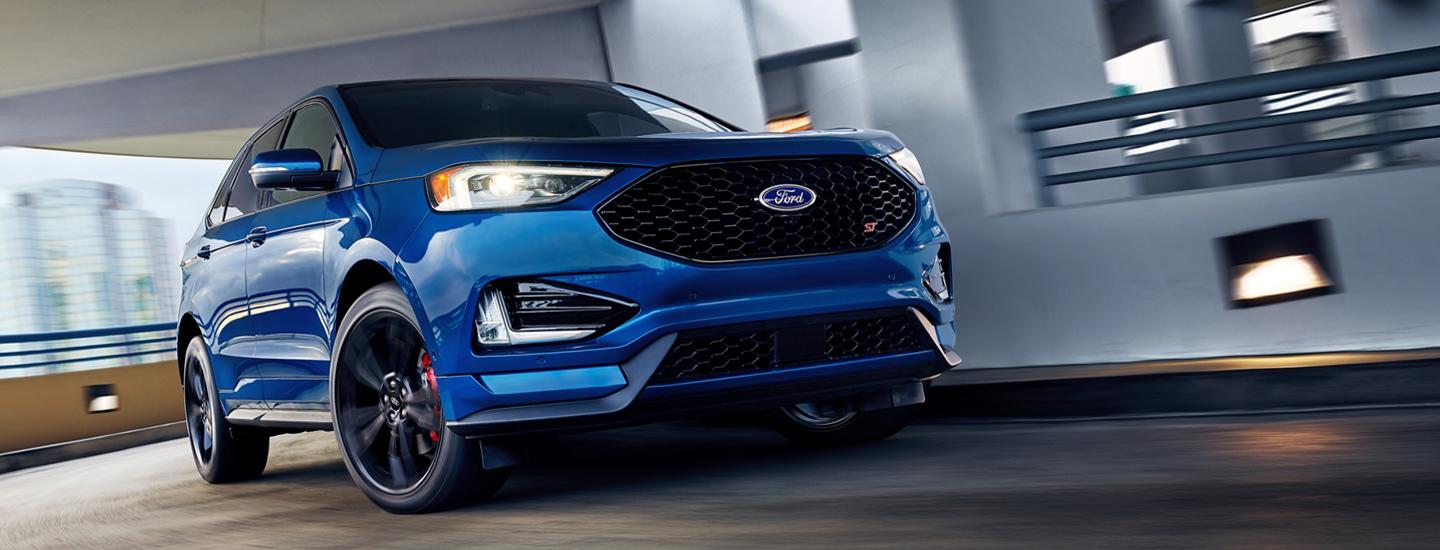 Front view of a Blue Ford Edge in motion