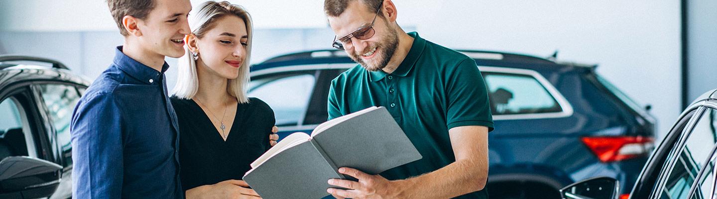Woman and Man discuss details of car sale in dealership with another Man