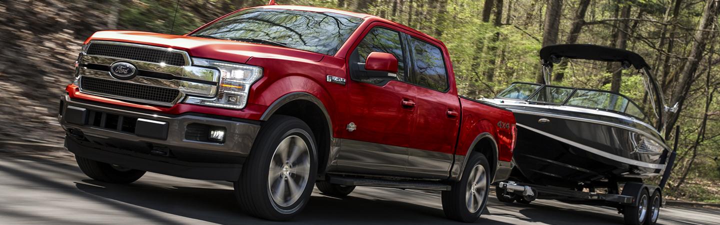 Side view a red 2020 Ford F-150 towing a boat