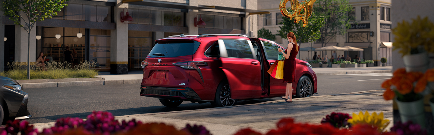 Red 2020 Toyota Sienna parked on city street with woman carrying shopping bags