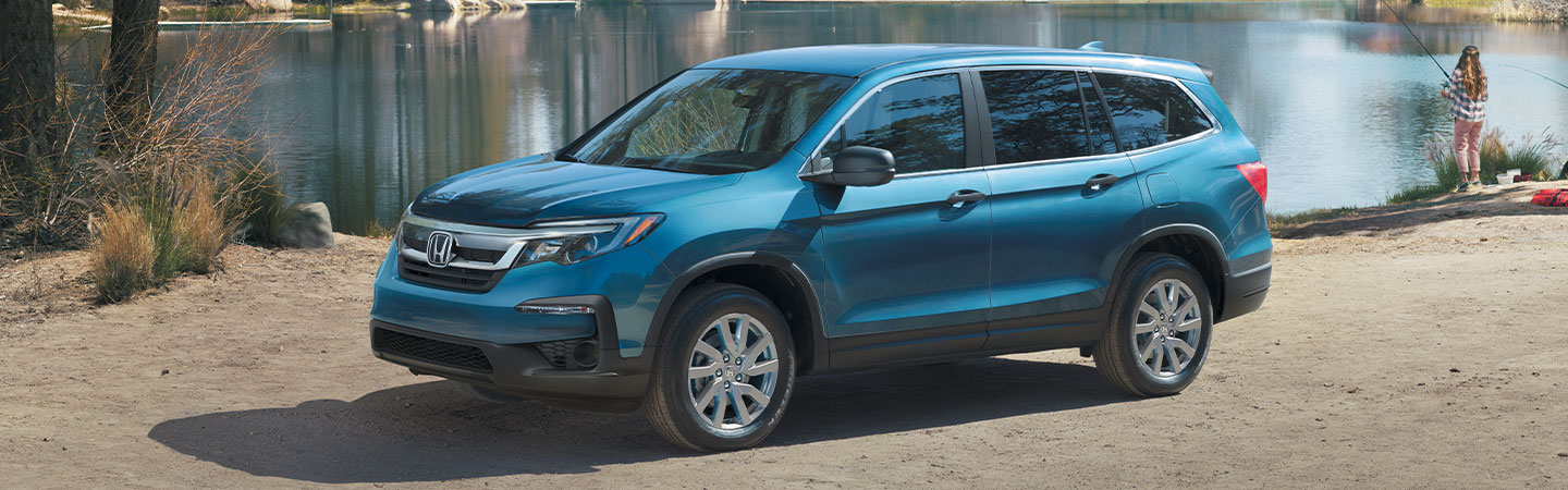 Blue Honda Pilot parked next to a lake. 