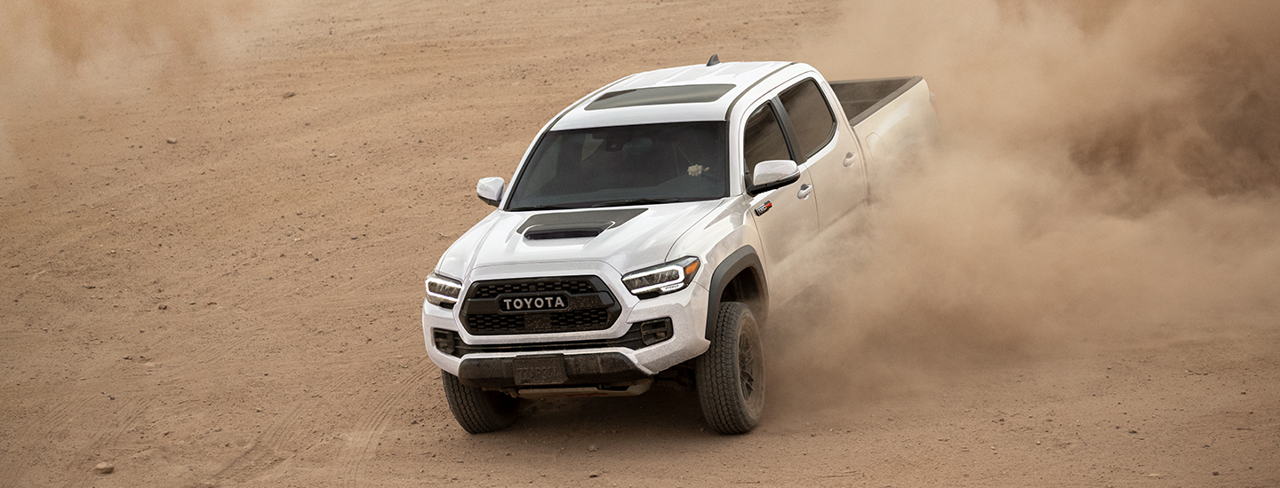 White 2021 Toyota Tacoma driving through dirt
