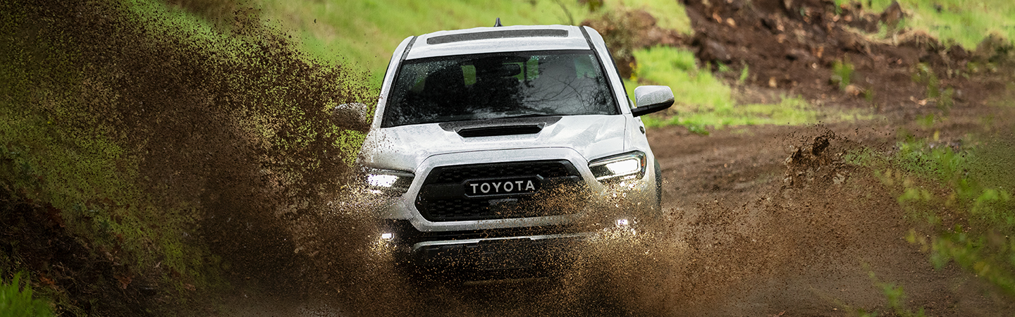  White 2021 Toyota Tacoma driving through mud on trail
