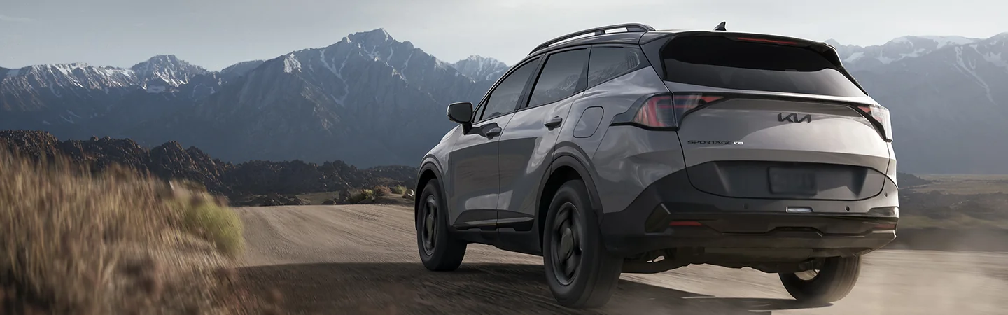 2026 Kia Sportage driving toward mountains on a dirt road