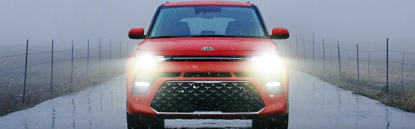 Red 2021 Kia Soul driving in the rain with the headlights on